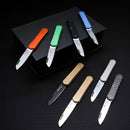 Eight Fox Knives with varied colored handles and stainless steel blades displayed on and around a black box.