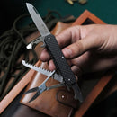 Hand holding Fox Knives VULPIS FX-VP130-SF5 BK multitool knife with open blade and tools on a leather surface.
