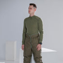 Man wearing green thermal Czech army M85 liner pants standing against gray background