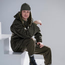 Man wearing genuine German Army military winter pile cap in olive drab with matching cold weather gear sitting on steps