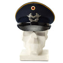 Vintage blue German Luftwaffe air forces peaked visor cap with military insignia and yellow piping displayed on white bust