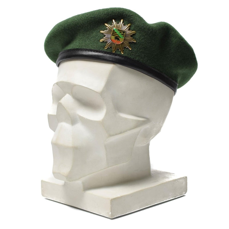 Genuine German police green wool beret with metal cockade insignia displayed on white mannequin head