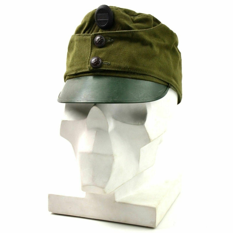 Vintage Hungarian army peaked cap in olive green with military badge and protective visor on white mannequin head
