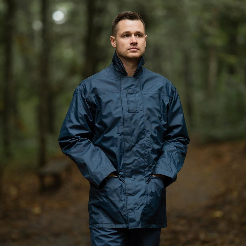 Man wearing original British RAF waterproof blue parka raincoat standing outdoors in forest setting
