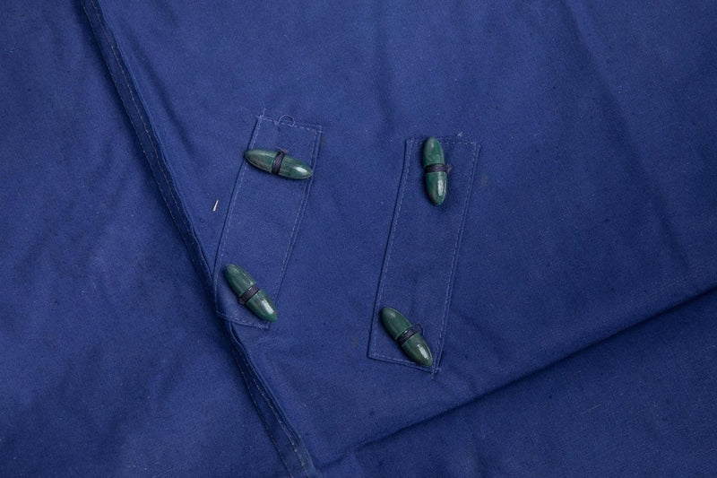 Close-up of blue waterproof Romanian military tent tarpaulin fabric with reinforced stitching and green toggle fasteners.