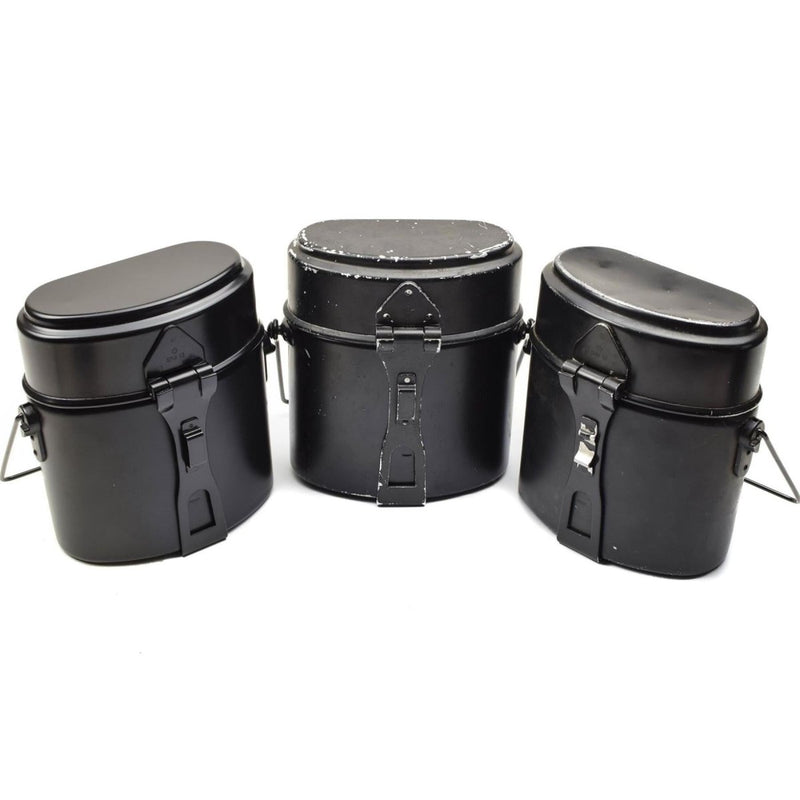 Three black vintage Swedish military surplus mess kits for outdoor cooking arranged side by side on white background