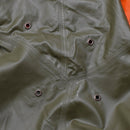 Close-up of olive green waterproof Swiss army rain jacket with taped seams and ventilation eyelets on durable polyamide fabric.
