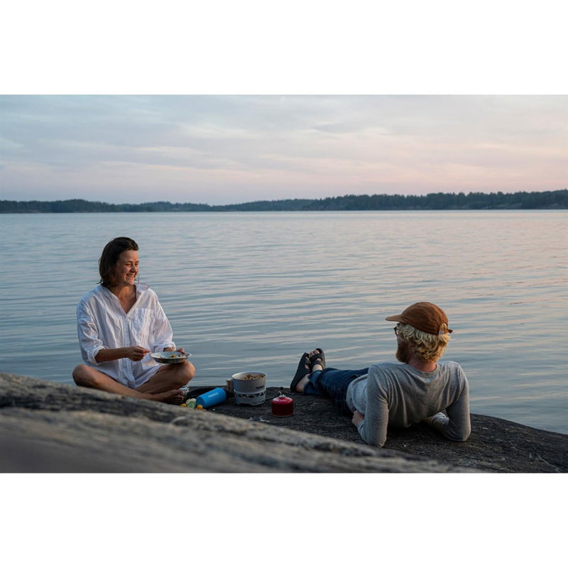 Two people enjoying a meal cooked with Primus Essential Stove Set 2.3L pot pan by the lakeside during camping trip