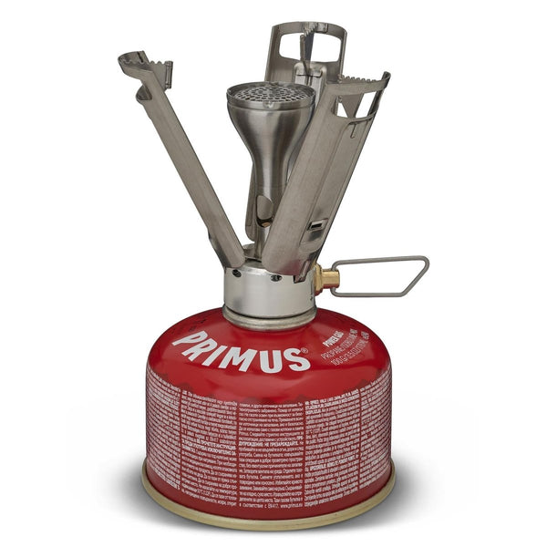 Primus Firestick Titanium lightweight camping stove mounted on red gas canister with unfolded pot supports.